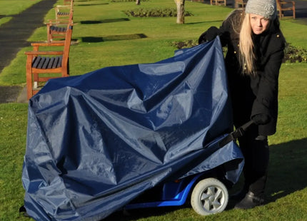 Vrouw trekt een duurzame scootmobiel hoes aan in een park, beschermt tegen neerslag en vuil.